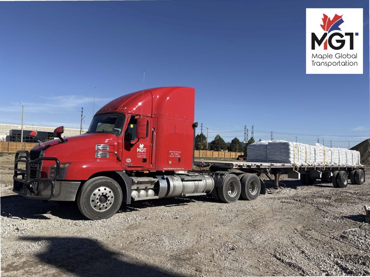 Maple Global Transport red semi truck with flatbed trailer hauling construction materials in Ontario